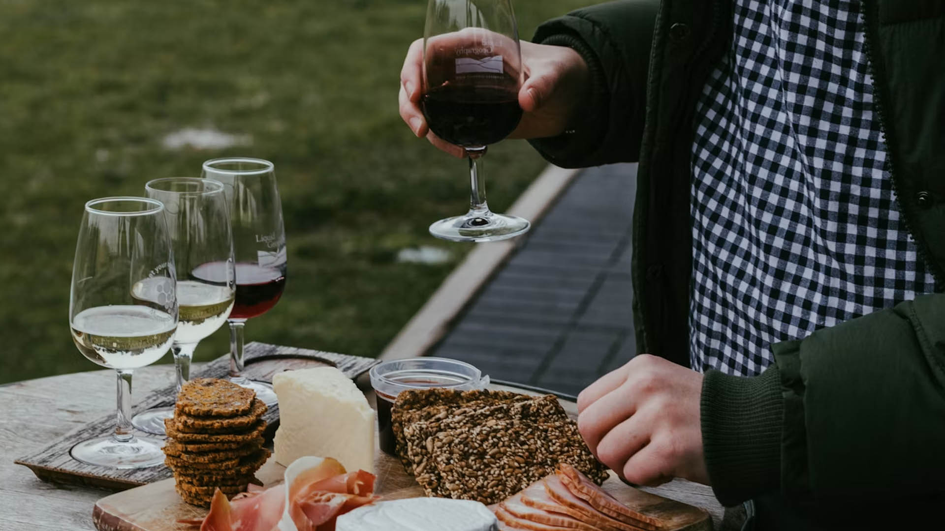 Copas de vino junto a una tabla de quesos, embutidos y panes artesanos